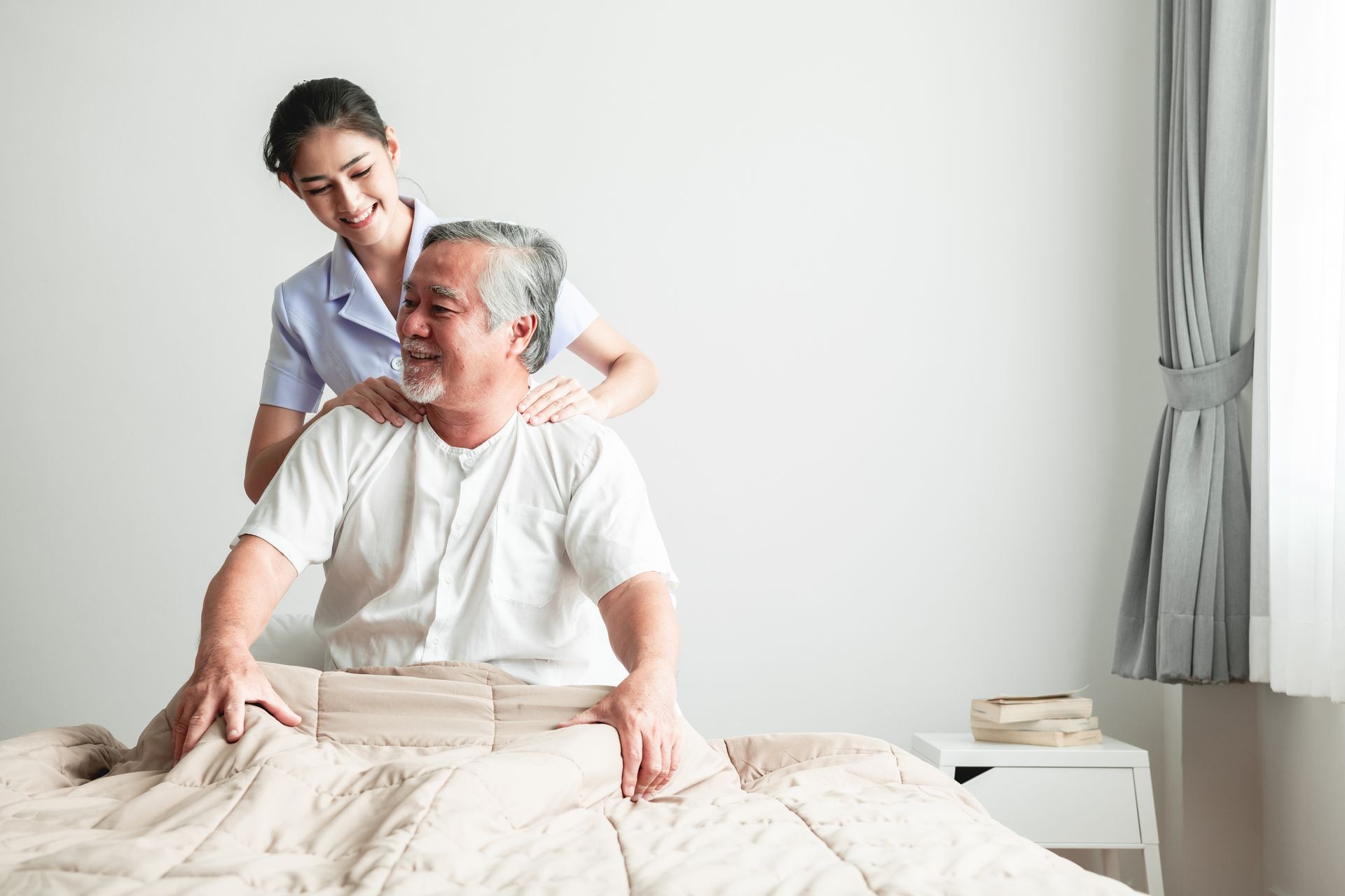Young attractive physiotherapist working on senior man. Beautiful asian woman working with asian senior man's shoulder. Senior home caretaker service concept.